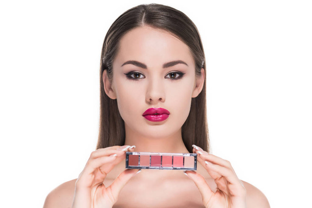 beautiful young woman holding palette of makeup shadows isolated on white - Foto, imagen