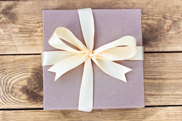 Gift. Craft box with a bow on wooden boards. - Foto, Imagen