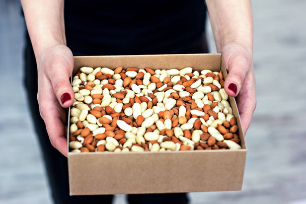 Female hands hold a box of nuts and dried fruits.  - Foto, Bild