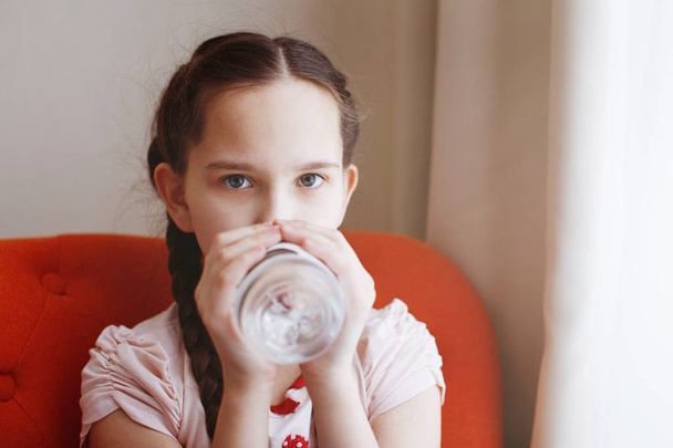 Una giovane bella ragazza con le trecce beve acqua da una bottiglia
. - Foto, immagini