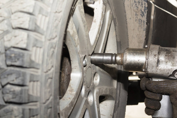 Las manos mecánicas del coche reemplazan los neumáticos sobre ruedas en el garaje. Trabajador técnico mecánico que instala la rueda del coche en mantenimiento. Concepto de instalación de neumáticos
 - Foto, imagen