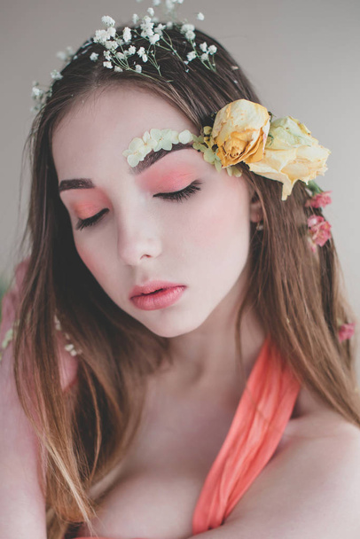 Kosmetiikka ja manikyyri. Lähikuva muotokuva houkutteleva nainen kuivat kukat hänen kasvonsa ja hiuksensa, pastelliväri, täydellinen meikki ja iho sinisellä pohjalla. Tuore, trendikäs, kevät korjattu muotokuva
 - Valokuva, kuva
