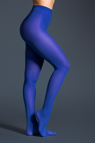 Female legs in blue pantyhose on dark background - Fotó, kép