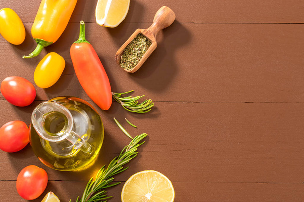 Olive oil, tomato, lemon, pepper and herbs on dark wooden table. - Photo, Image