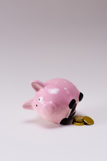close up view of pink piggy bank and pile of coins isolated on lilac - Photo, Image