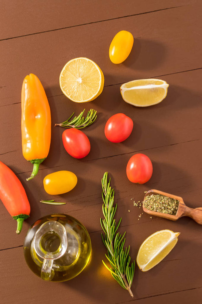 Olive oil, tomato, lemon, pepper and herbs on dark wooden table. - Foto, afbeelding