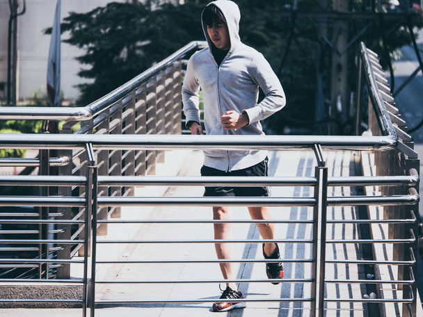 Jeune homme athlétique jogging sur le pont de la ville le matin
. - Photo, image