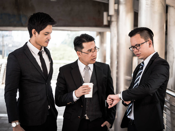 Les gens d'affaires asiatiques parlent ensemble avec le sentiment de stress tout en se tenant devant l'immeuble de bureaux
. - Photo, image