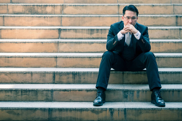 街の階段の上に座って心配のアジア系のビジネスマンの肖像画。コピー スペース - 写真・画像