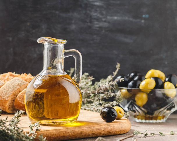 Glass bottle of olive oil with olives - 写真・画像