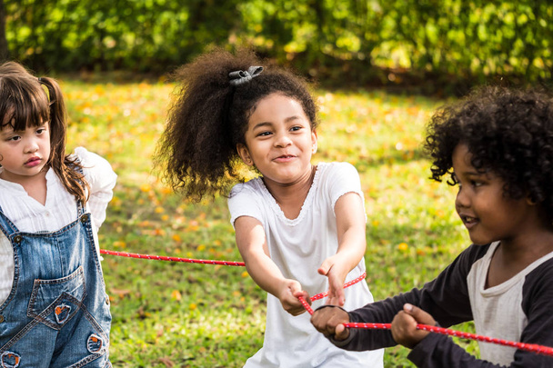 Egy kicsi lány játék kötélhúzás a barátaival, parkban - Fotó, kép