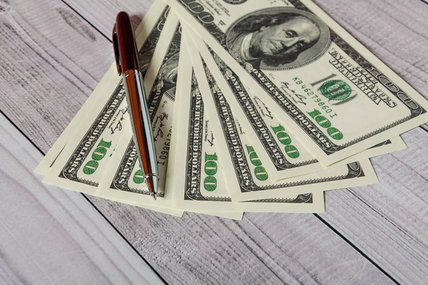 Jegyzettömb, toll és pénzt a világos fából készült háttér - Fotó, kép