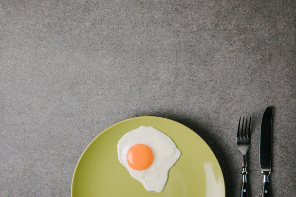 felülnézete a lemez és a villát kés a szürke friss sült tojás  - Fotó, kép