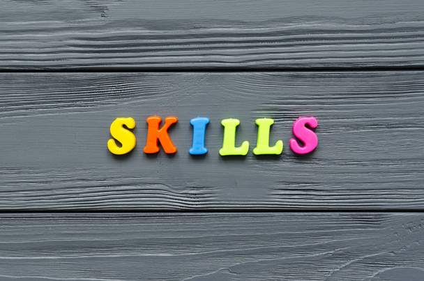 word "skills" of colored plastic magnetic letters on grey wooden - Photo, Image