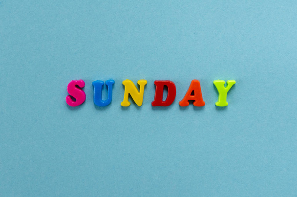 word "sunday" of colored plastic magnetic letters on blue paper  - Foto, Imagem
