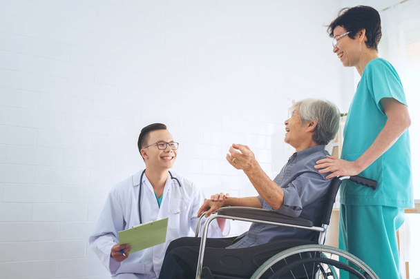 Arts die van de oudere patiënt hand in een wheelchai, waardoor su - Foto, afbeelding