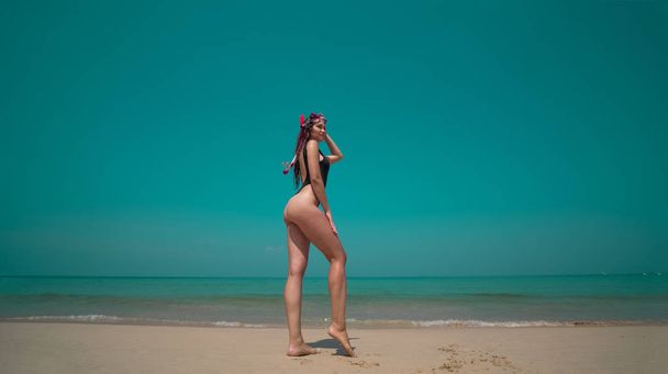 Piękna młoda kobieta w strój kąpielowy z rurką stojący przy piaszczystej plaży nad morzem i niebem tło. Ładna dziewczyna korzystających słoneczny, letni dzień na jej Plaża Tropikalne wakacje - Zdjęcie, obraz