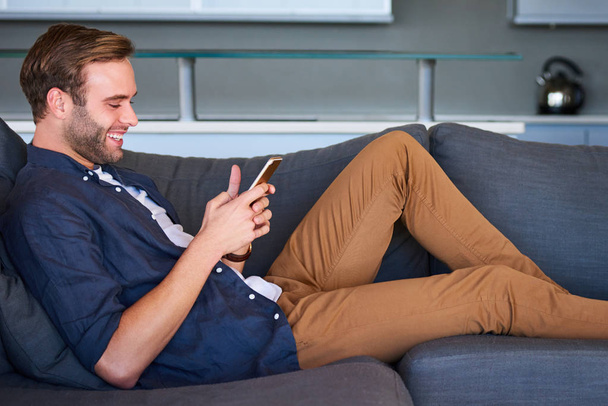 Side view of handsome male on couch with mobile phone - Φωτογραφία, εικόνα