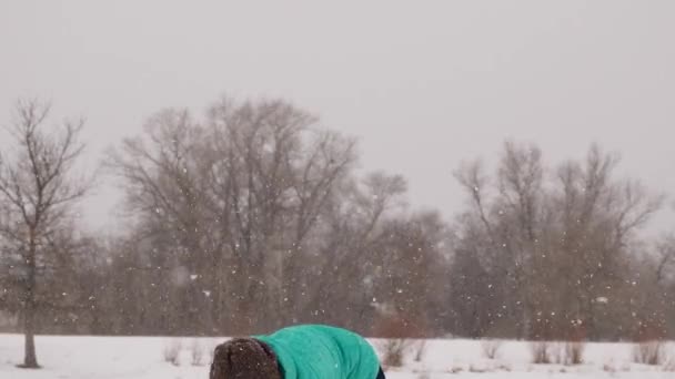 blij en zorgeloos vrouw spelen sneeuwballen in het sneeuw Park. Er is sterke sneeuwstorm. - Video