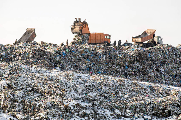 Dump trucks afval lossen over enorme sanitaire vulling. De vervuiling van het milieu. Verouderde technologie - Foto, afbeelding
