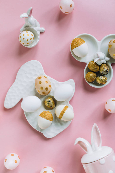 Golden glitter Easter eggs on plate in shape of rabbit on pink background - Foto, Imagem