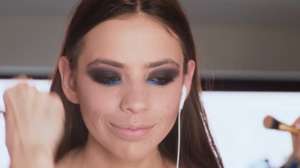 Make-up artist applying bright lipstick on model's lips. Makeup artist doing makeup for girl indoor. - Πλάνα, βίντεο