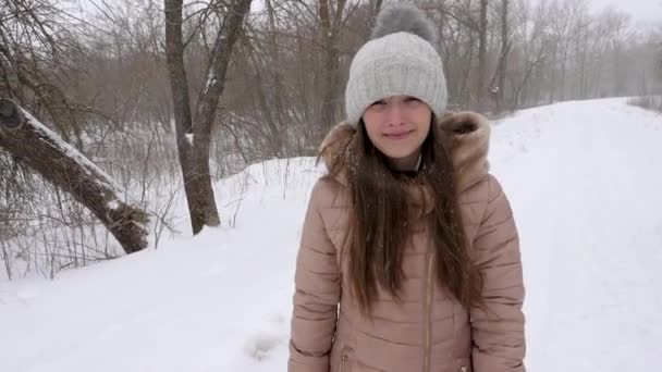 Gelukkig meisje loopt door sneeuw bedekte stad en glimlacht. Sneeuwstorm. Beweging Winter.Slow.. - Video