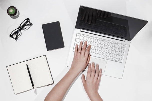 Mani femminili stampa testo sul computer portatile. Vista dall'alto del moderno spazio di lavoro con laptop, cactus, occhiali, notebook e penna
. - Foto, immagini