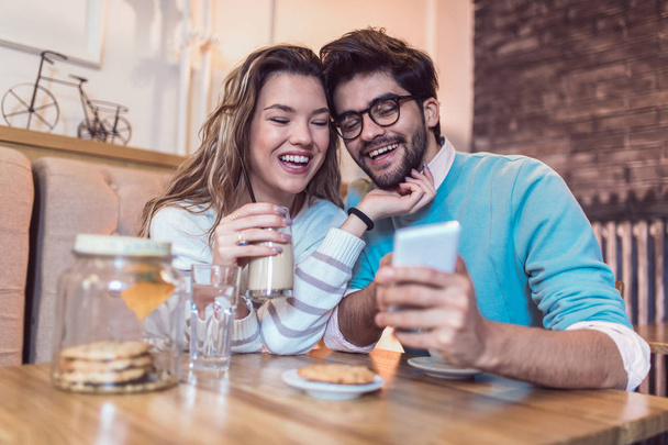  Любящие пары сидят в кафе, пьют кофе и пользуются телефоном
. - Фото, изображение