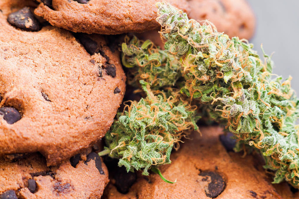 Des cookies avec du cannabis et des bourgeons de marijuana sur la table. Concept de cuisson avec de l'herbe de cannabis. Traitement de la marijuana médicale pour utilisation dans l'alimentation, Sur un fond noir
 - Photo, image