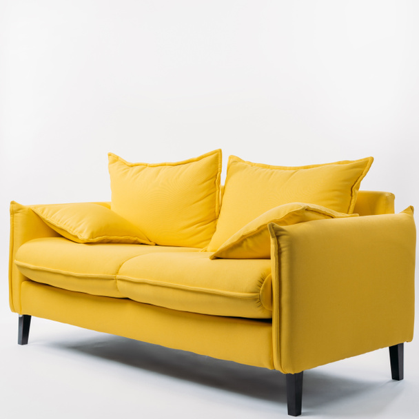 Studioaufnahme einer gelben Couch mit Kissen, auf weißem Hintergrund - Foto, Bild