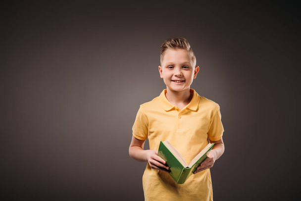 preteen boy holding book, isolated on grey - Fotó, kép