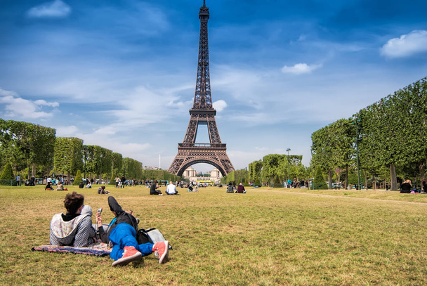 Teenager couple lying on the grass of Mars field near the Eiffel tower, copy space. - Photo, image
