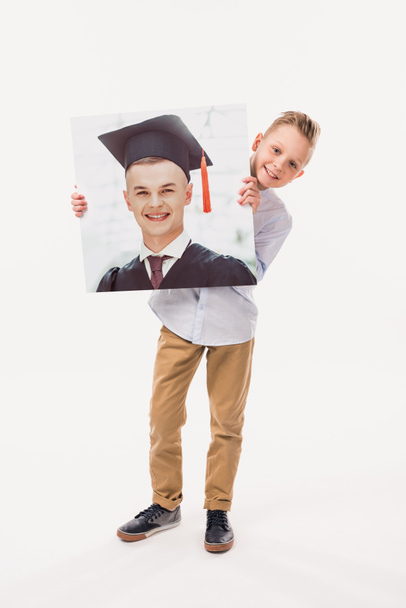 niño sonriente fingiendo ser un estudiante graduado, aislado en blanco
  - Foto, imagen