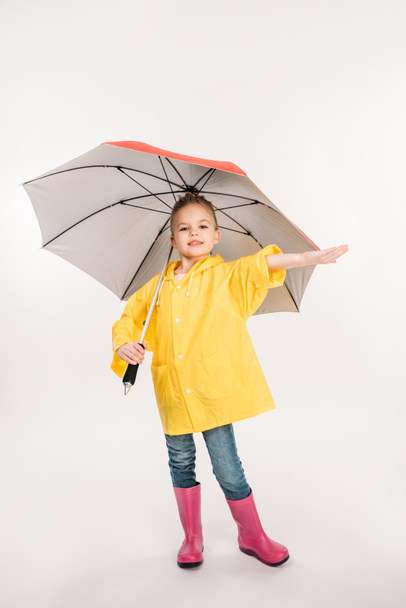pretty child in rubber boots, yellow raincoat with umbrella, isolated on white - Foto, Imagem