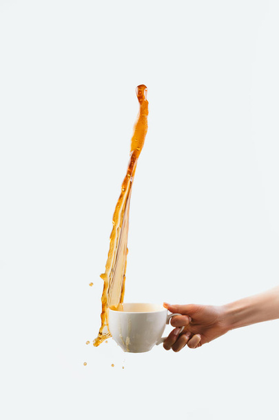 cropped view of hand holding big cup of coffee with splash, isolated on white - Foto, Bild