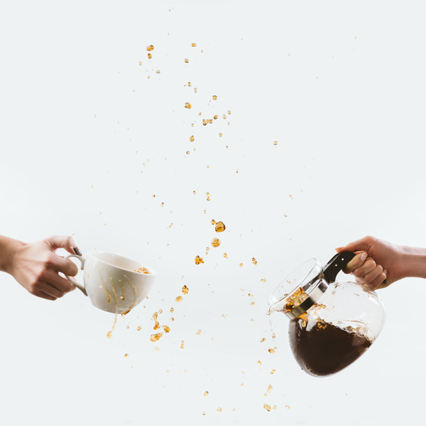 cropped view of hands with cup and glass pot with drops of coffee, isolated on white - Photo, Image