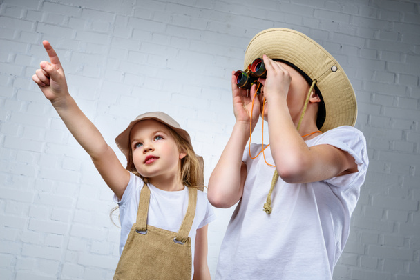 children in safari costumes and hats pointing and looking in binoculars - Photo, Image