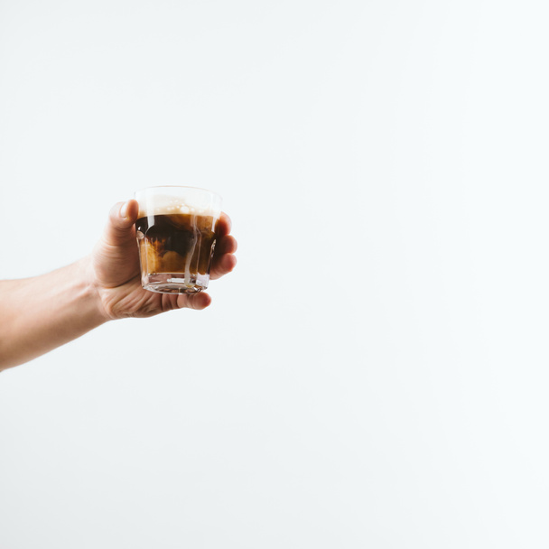 cropped view of hand holding glass full of coffee with milk, isolated on white - Photo, Image