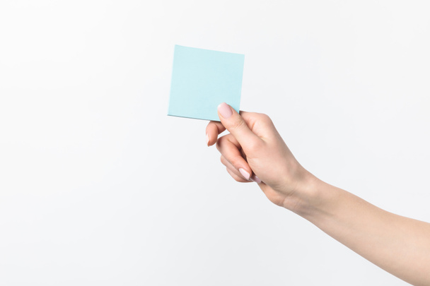 cropped shot of woman holding blank blue sticky note in hand isolated n white - Photo, Image