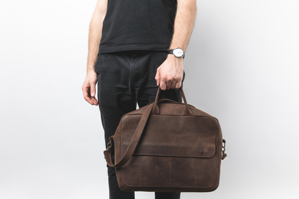vista parziale dell'uomo che tiene in mano la borsa in pelle isolata su bianco
 - Foto, immagini