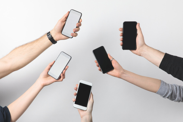 visão parcial de grupo de pessoas com smartphones com telas em branco isoladas em branco
 - Foto, Imagem
