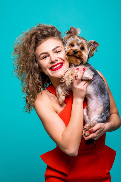 Nahaufnahme Porträt von lächelnden jungen attraktiven Frau umarmt yorkshire terrier isoliert Frontansicht auf Farbhintergrund. - Foto, Bild