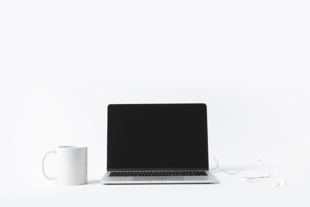 close up view of laptop with blank screen, earphones and white mug isolated on white - Photo, Image