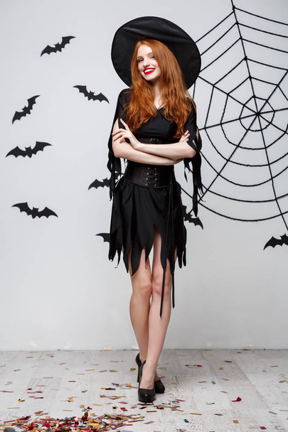 Halloween witch concept - Full-length of Happy Halloween Strega posa su sfondo grigio scuro studio con pipistrello e ragnatela
. - Foto, immagini