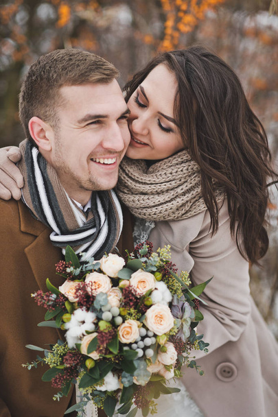 The newlyweds smile happily on a winter walk among the berries o - Foto, afbeelding