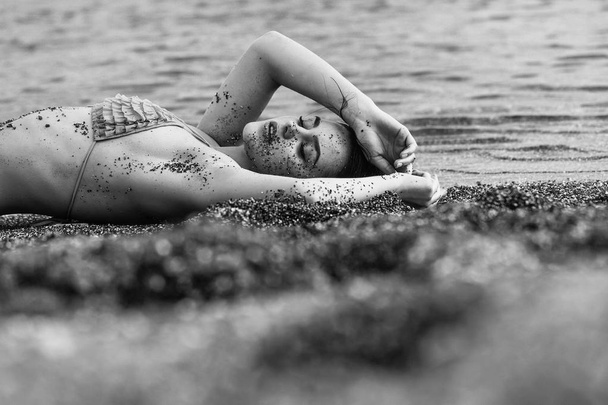 Pretty girl in yellow swimsuit sleeping on sea beach - Foto, immagini