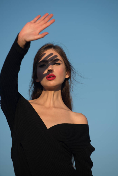 Hairdresser and skincare, summer fashion. Elegant woman with long hair. Beauty and fashion, cosmetics. girl with red lips on blue sky background. Fashion look of stylish woman in black, makeup. - Fotó, kép
