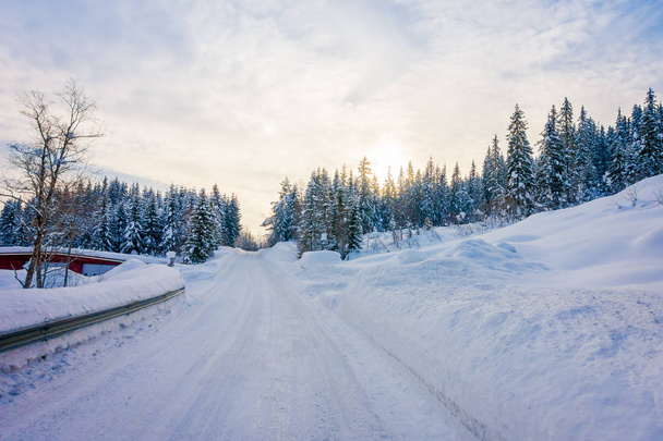 Outdoor view of winter road covered with heavy snow and ice in the forest and a gorgeous sunset view - Fotografie, Obrázek