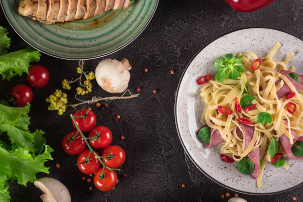 Italian spaghetti. Tagliatelle pasta with ham. Selective focus. Black background. Top view - Fotó, kép